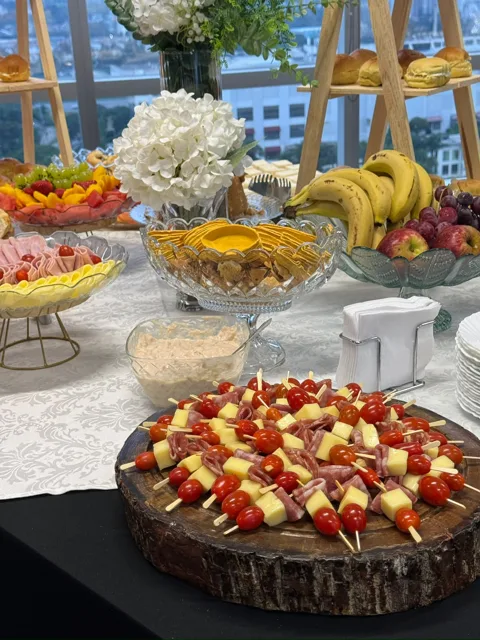 Mesa de buffet com frutas, flores e espetinhos