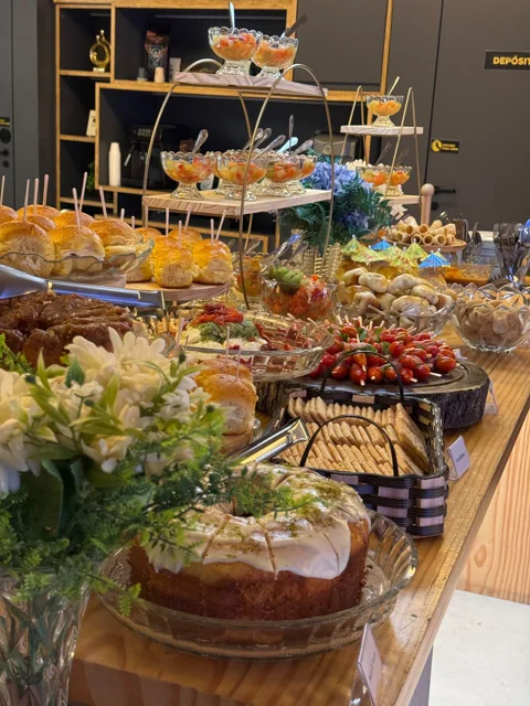 Montagem Áurea com bolos, mini sanduíches, espetinhos e flores